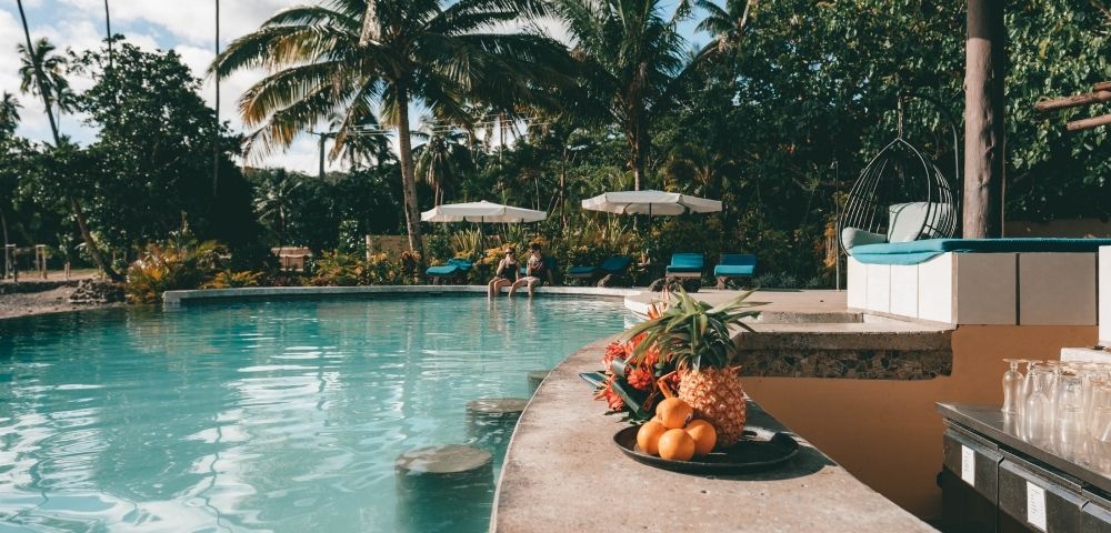 swim up bar with fruit spread and people sitting in the background with white umbrellas