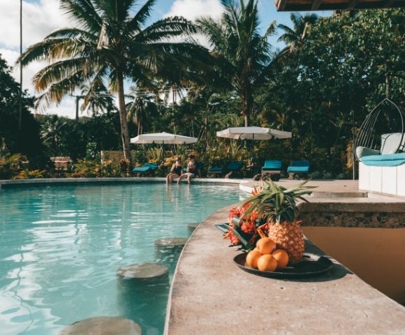 swim up bar with fruit spread and people sitting in the background with white umbrellas