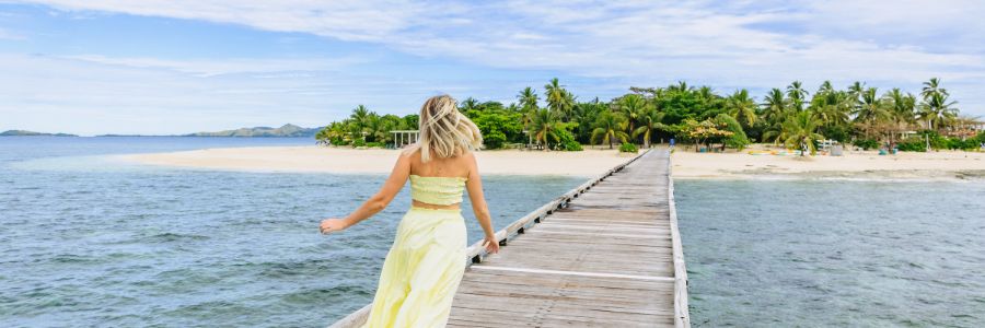 my-fiji-woman-in-bright-yellow-dress-running-down-jetty-of-malamala-bach-club