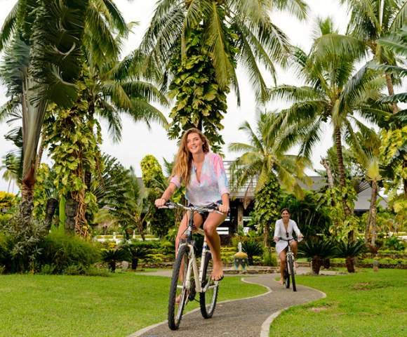 MYHOLIDAY-THE-WARWICK-FIJI-TWO-WOMEN-RIDING-BIKES-DOWN-GARDEN-PATH